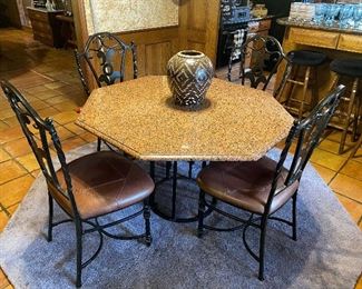 Granite octagonal table with 4 wrought iron chairs and iron base.