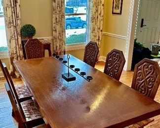 This dining set was purchased in the early 1950s by our homeowner's in-laws. It was hand carved in Brittany, France by master carpenters. Truly unique and a show-stopper! The seats are woven in leather!  