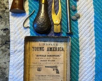 This rare and unusual pistol was invented by John P. Lindsay and manufactured in the early 1860s in extremely limited quantities with only several hundred produced. The pistol has a single barrel that holds two superposed loads. The pistol has two hammers and one trigger enabling the user to fire each charge separately. The barrel is a full octagon with a stepped down contour with wide flat sides at the breech end half and contoured rounded top with a sighting groove. The right rear of the barrel is marked "LINDSAY'S/YOUNG-AMERICAN/MAN'F'D BY/J.P. LINDSAY-MAN'FG CO./NEW-YORK" and features a scroll engraving. The left rear of the barrel is engraved with a flag and shield motif flanked by a large lion and eagle. The bottom barrel flat is marked "PATENT'D. FEB. 8. 1859/PATENT'D. OCT. 9. 1860" and the serial number "208" is marked just ahead of the frame. The brass frame features a scroll and punch dot engraving on the sides and back strap. The serial number is also on the frame under the 