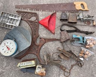 Single man saw,  Double ice cube tray, red dust pan from DeMontels Furniture store, assorted cowbells with original clappers, meat grinder with extra parts, lots of wooden spools, old harness with blinders, tin gravel truck from the 50s, cast-iron school desk piece marked with a number 3, hanging scale