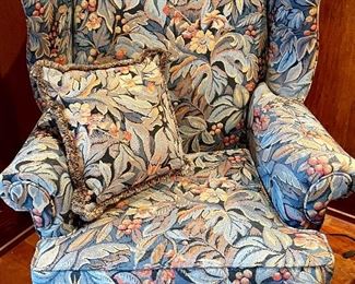 Large, floral wing chair with Chippendale legs, blue ottoman and throw pillow. This is an imposing piece of furniture!