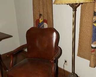 Antique cylindrical floor lamp with deer finial, a set of woman with outstretched arms holding up the lamp at the base, and a leather shade. 