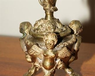 This incense burner is brass, has a tripod of cherubs with a monkey on the top of the lid