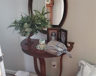 Oval entry hall mirror over a half moon wall table. Mint