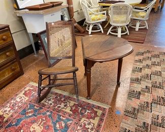 Cute tripod table with drop leaves and cane rocker sitting on a Karastan rug.
