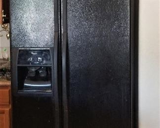 Side-by-side black refrigerator/freezer with water and ice.