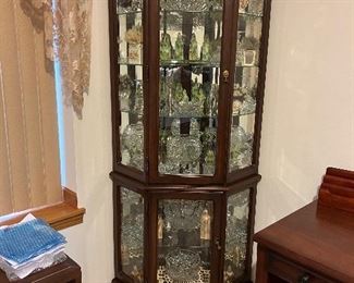 A lighted corner cabinet w/ lots of glassware.