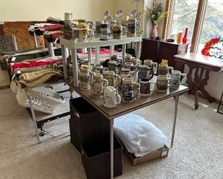 About 3 dozen beer steins and a sampling of the hundreds of fabric yards. Note: the antique parlor table and the matching end tables w/ pull out writing drawer and more…