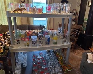 Top shelf - Pyrex measuring cups, Miller and Hamm and other beer and pop glasses                                                                     Middle shelf - various glasses *singles and doubles)        bottom - sets of glasses including a red fireman's hat design                                         