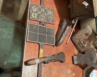 On the left is an orphaned iron! Circa 1800s it’s a candy maker, waffle mold. 
Far right you have the Indian Chief DOE-WAH-Jack Round Oak stove lid, via the center there is a hot coal fitted iron. Some great Antiques!!