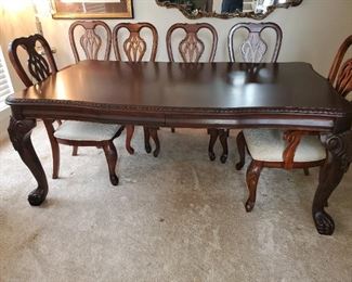 The table is a bit darker than the chairs and has claw feet.