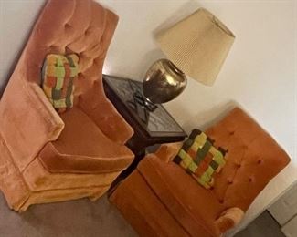 Orange velvet chairs and gold lamp and glass end table with wooden legs and top'