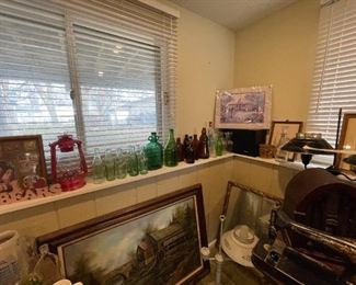 Collection of vintage glass bottles including Coca-Cola, milk jugs, etc. Plenty of artwork displayed throughout the sale as shown by the several pieces in the photo.