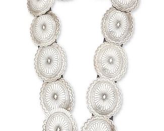 3
Late 20th/21st century
Suzie James (1954-2012, Dine)
A Navajo sterling silver concho belt
Stamped: Suzie James / Sterling
With ten stamped oval conchos and buckle, all mounted to a black leather strap, plus one loose concho, 2 pieces
Buckle and each concho: 2.5" H x 3" W; belt: 1.375" H x 31.5" L<br />454.1 grams gross
Estimate: $600 - $800