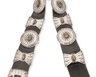 4
Early 20th century; Dine
A Navajo Concho Belt
Appears unmarked
Comprised of four large round conchos, five large butterfly conchos and a square belt buckle each with stamped motifs and set with turquoise, all set to a wide black leather belt
Buckle: 3.5" H x3.5" W, 1" opening; each round concho: 3.5" Dia.; each butterfly: 2.5" W; belt: 3" H x 40" L<br />880.9 grams gross
Estimate: $1,000 - $1,500