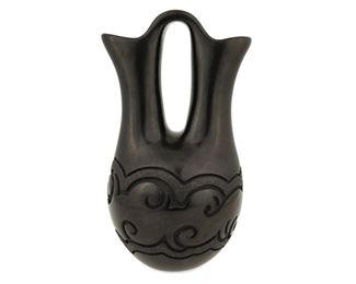 86
Late 20th century
Linda Tafoya-Oyenque (B. 1962, Santa Clara Pueblo)
A Pueblo blackware pottery wedding vase
Signed to base: Linda Tafoya-Oyenque / Santa Clara -San Juan
A small blackware wedding vase with carved curvilinear Avanyu motif and micaceous accents
9" H x 4.5" Dia.
Estimate: $500 - $700