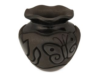 88
Late 20th century
Harrison Begay, Jr. (B. 20th Century, Dine/Santa Clara Pueblo)
A small Pueblo blackware pottery vessel
Signed to base: Harrison [within pot pictogram]
A carved blackware pottery low bowl with a fluted rim and burnished and matte micaceous sections with floral and butterfly motifs
4.5" H x 4.5" Dia.
Estimate: $200 - $400