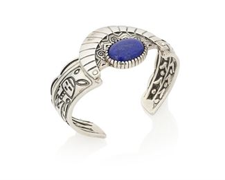 159
Late 20th century
A Relios Southwest Style Cuff Bracelet
Stamped for Relios; further stamped: 925
A stamped sterling silver cuff with corn motif to one terminal and a Kokopelli figure to other, centering a lapis lazuli cabochon in a crescent moon surround
6.75" total inner C x 1.25" H, with a 1.125" gap<br />49.6 grams gross
Estimate: $200 - $300