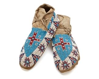 296
20th century
A Pair Of Plains Beaded Hide Moccasins
Each hide moccasin with a beaded central red cross on a blue field, with a lower band border of white with alternating red and blue star and stepped geometric motifs, 2 pieces
Each: 10.75" L x 3.5" H x 4" W
Estimate: $400 - $600