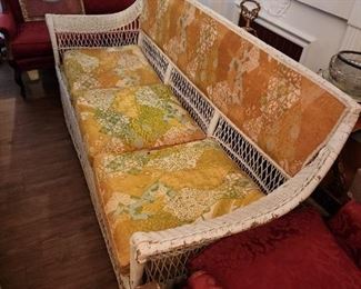 Wicker couch with upholstered seat.