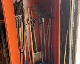 Interior of steel storage cabinet with shovels, rakes, snow shovels, etc.