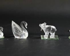 252	Lot of 8 Swarovski Crystal Animal Figurines	Lot of 8 Swarovski crystal animal figurines. Includes two elephants, a koala bear, a groundhog, an anteater, a bear with trout, two swans, and five mirrored display plates. All figurines include a Swarovski swan or block logo maker's mark. Small elephant figurine is missing one ear. Large elephant measures 2 1/2" W x 1 1/2" D x 2 1/4" H.
