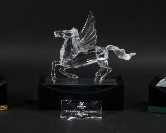 253	Swarovski Crystal 'Fabulous Creatures' Figurines	"Swarovski 'Fabulous Creatures' figurine set. Includes Unicorn, Dragon, Pegasus, corresponding display stands, and a title plaque. All figurines include a Swarovski swan maker's mark and original packaging.
Stand dimensions: 5 7/8"" W x 2 3/4"" D x 2"" H. 
Minor scratching on one stand."
