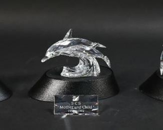 254	Swarovski Crystal 'Mother and Child' Figurine Set	"Swarovski crystal 'Mother and Child' figurine set. Includes ""Save me"" - the Seals, ""Care for me"" - the Whales, ""Lead me"" - the Dolphins, three display stands, and a title plaque. All figurines include a Swarovski swan maker's mark and original packaging.
Whales measure 3 3/4"" W x 2 3/4"" D x 4"" H.
Small chip on the tip of one end of a dolphin's tail and some scratches on the tops of the display stands."
