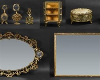 259	10 Piece Gilt Metal Dresser Set	10 piece gilt metal dresser set, including mirrored tray with 2 matching perfume bottles and a lidded box all with cherub motif, pair of perfume bottles, single filigree perfume, dresser box, jewelry vitrine, rectangular mirrored tray. Oval  tray 26 3/4" x 18", pair of cherub perfumes 9 1/2"H including stoppers, rectangular tray 12 1/8" x 20 1/8". Some staining to fabric on dresser box lids, pieces missing from edges of rectangular tray.
