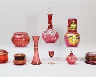 332	9 Pieces Bohemian & Decorated Cranberry Glass	"9 pieces cranberry glass including Bohemian and enamel decorated. Hand painted decanter with floral design, Bohemian tumble up, enamel decorated bud vase, enamel decorated cordial, enamel decorated perfume, gilt enamel decorated bowl, gilt decorated lidded box, lidded box with gilt and cherub enamel decoration, enamel decorated lidded box with snowflake motif. Tumble up 7 3/4""H, snowflake box 2 5/8""H x 4 3/4""-diameter.

Inside end of stopper on decanter chipped and losses to gilt on rim of decanter, losses to gilt decoration on lid of tumble up, chips to rim of bud vase and losses to decoration, stopper frozen on perfume, roughness to rim of gilt decorated bowl, losses to gilt decoration on lidded box, repair to snowflake box and minor losses to decoration on lid, internal line in snowflake box."

