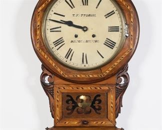372	T. Fattorini Inlaid English Wall Clock	T. (Thomas) Fattorini, Bolton & Skipton. Wooden wall clock with parquetry decoration and painted metal dial. 27"L x 16 1/4"-diameter. Splits to wood along outside of face, fading and paint loss to numerals and letters on dial, chips to paint along edges of dial, losses to patina on metal around face and at hinge.
