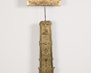 374	Charvet French Morbier Style Clock	Charvet a la Tour du Pin French Morbier style wag-on-the-wall clock. Repousse Sun King over face, with repousse decoration throughout. 60"L. Piece broken off of pendulum (partial piece present), additional weights added to bottom of pendulum, crazing to dial.
