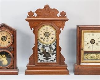 375	3 Shelf Clocks Gilbert, Ingraham, Seth Thomas	4 wooden mantel / shelf clocks. Wm. L. Gilbert gingerbread clock, 21 3/4"H; Ingraham "Doric" shelf clock, 15 7/8"H; Seth Thomas shelf clock with reverse painted panel with patriotic motif, 15 1/4"H. Seth Thomas clock crazing to face, hand missing, paint loss to reverse painting, screws missing to hold face in place; Ingraham clock wear and discoloration to face, minor losses to bird decoration; Gilbert clock missing support piece on back, no pendulum, base separating at corner.
