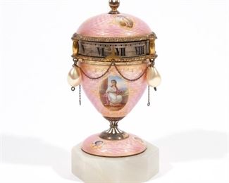 ENAMELED GUILT METAL URN/ORBIT CLOCK | Circa 1920, pink guilloche enamel case with portraits of angels and classically draped figures, 2 simulated baroque pearls dangling from urn. The quilt chapter ring turns against fixed pointer, stem to wind and to set. Swiss movement made in Austria.
h. 4-1/2 w. 2in
(245) Almost identical larger clock sold @ Christies, 13 May 2007 N.B. Descriptions are revised from a 1994 insurance appraisal by a noted N.Y.C. auction house Horologist