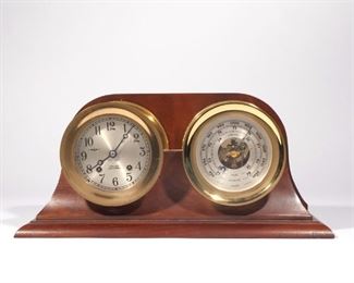 CHELSEA SHIP'S BELL CLOCK & BAROMETER | A Chelsea Ship's Bell clock with a 4-1/2 in. silvered dial with Arabic numerals and two keys, with a Chelsea barometer measuring in inches, centimeters, and millibars with engraved "CSX Corporation" dedication dated 1983, mounted as one in a wood mantel stand
h. 7-3/4 w. 16-3/4 d. 4-3/8 in.