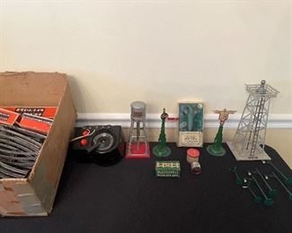 Dining Room:  A box of vintage LIONEL "O" gauge track and an LW "Trainmaster" Toy Transformer (115 volts/60 cycles/125 watts) are priced as a set.  Also shown and priced:  Lionel water tank No. 38; a pair of train signals; a box set of battery operated street lamps; a Lionel silver rotary beacon No. 394; a box of PLASTICVILLE fence and gate; an "as is" round lantern with original box; and a set of six green plastic street signs and lamp posts.