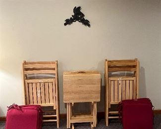 Lower Level:  This is the second set of four folding chairs and two separately priced sets of four seat cushions. The TV tray set matches the natural wood chairs.  The carved wood birds on the wall are also for sale.