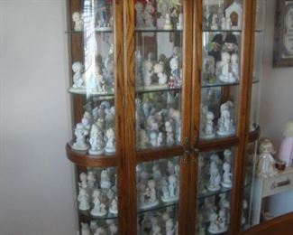 Oak china cabinet w curved glass filled with Precious Moments figures