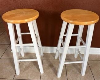 Two wooden stools with white legs and light brown seats