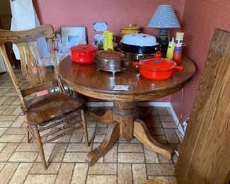Solid wood pedestal table and 4 chairs. MCM kitchen ware. Dansk red enamel casserole. Norman Rockwell Gorham plates and coffee mugs