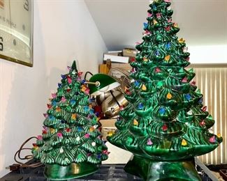 Two ceramic Christmas trees, smaller tree missing some light bulbs