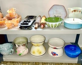Close-up view of Fire King peach luster dishes, cast iron molds, rolling pins, Mid-Century bowls, casseroles, Hull teapot, bowls, etc.