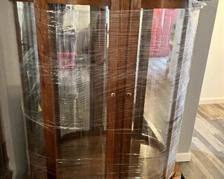Beautiful oak curio cabinet with glass shelves. It is wrapped in plastic for easy moving.