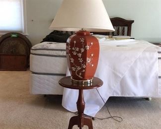 Vintage Glass Ginger Jar Rust Table Lamp and The Bombay Company Side Table
Vintage 19" glass ginger jar rust table lamp, with hand painted cream flowers, cream lamp shade - powers on; The Bombay Company medium brown wood end table, H 21".