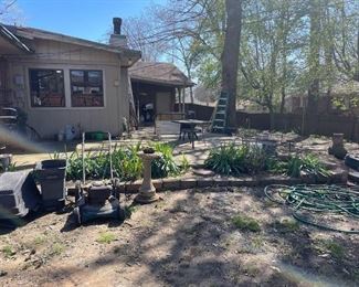 various items on the backporch for sale - planters, pots, bird baths, push lawnmower, table, swing, wicker bench with table end, and much more