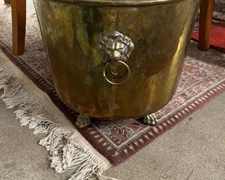 Brass bucket with lion heads and feet.