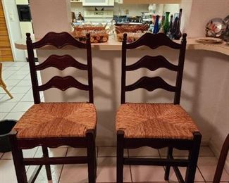 Pair of wood bar stools with wicker seats.