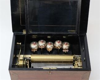 22	Swiss Cylinder 5 Bell Music Box	Swiss cylinder and five bell music box. Butterfly hammers. Decorated wooden case with lock and key. Working condition, cylinder rotates and plays, butterflies strike bells. Case 17 1/4"L x 10 5/8"D x 10 1/2"H, cylinder 9 1/4"L. Lid warped, does not close firmly and prevents lock from engaging; bubbling, chips and losses to veneer throughout case. From the collection of a prominent Connecticut family.
