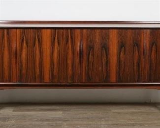 43	Bernhard Pedersen Danish Modern Sideboard	"Bernhard Pedersen (Danish, 20th century). Sideboard produced by Bernh. Pedersen and Son, circa 1965. Rosewood, four doors, three dovetailed felt-lined silverware drawers, two shelves, felt lined liquor storage drawer. No brand marks or Danish control tags present. Large square-form water stain to wood on top of sideboard. Nicks, scratches, scuffs, and stains to wood of top of sideboard and curved molding. Marks, nicks, and imperfections to wood of doors, front molding, and sculptured handles. Gray scuffs and marks to left and right sides of sideboard and dowel form legs. Slight separation of back paneling from sideboard. 

32 1/2"" H x 87 3/8"" L x 17 1/4"" D"

