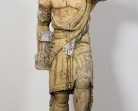 45	Cigar Store Indian in the Style of Thomas Brooks	"Cigar store Indian trade figure in the style of Thomas Brooks (American, New York, 1828-1895). Late 19th/early 20th century. American Indian chief with polychromatic tobacco leaf headdress with left hand raised, right hand holding bundle of cigars, left foot raised on block. Separation of portion of wood from center headdress leaf. Splits and cracks to wood throughout base, body of Indian, and headdress. Wear, fading, chips, flaking, and losses to paint and wood throughout base and Indian. 

14"" W x 15 3/4"" D 72 3/4"" H"
